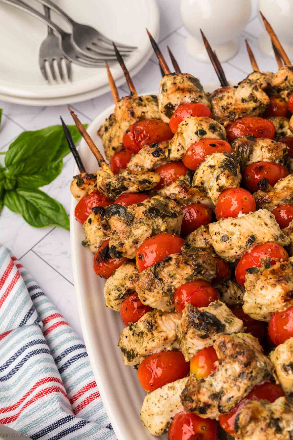 Grilled Pesto chicken kabobs stacked on a platter