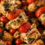 Chicken skewers with tomatoes and herbs on sticks.