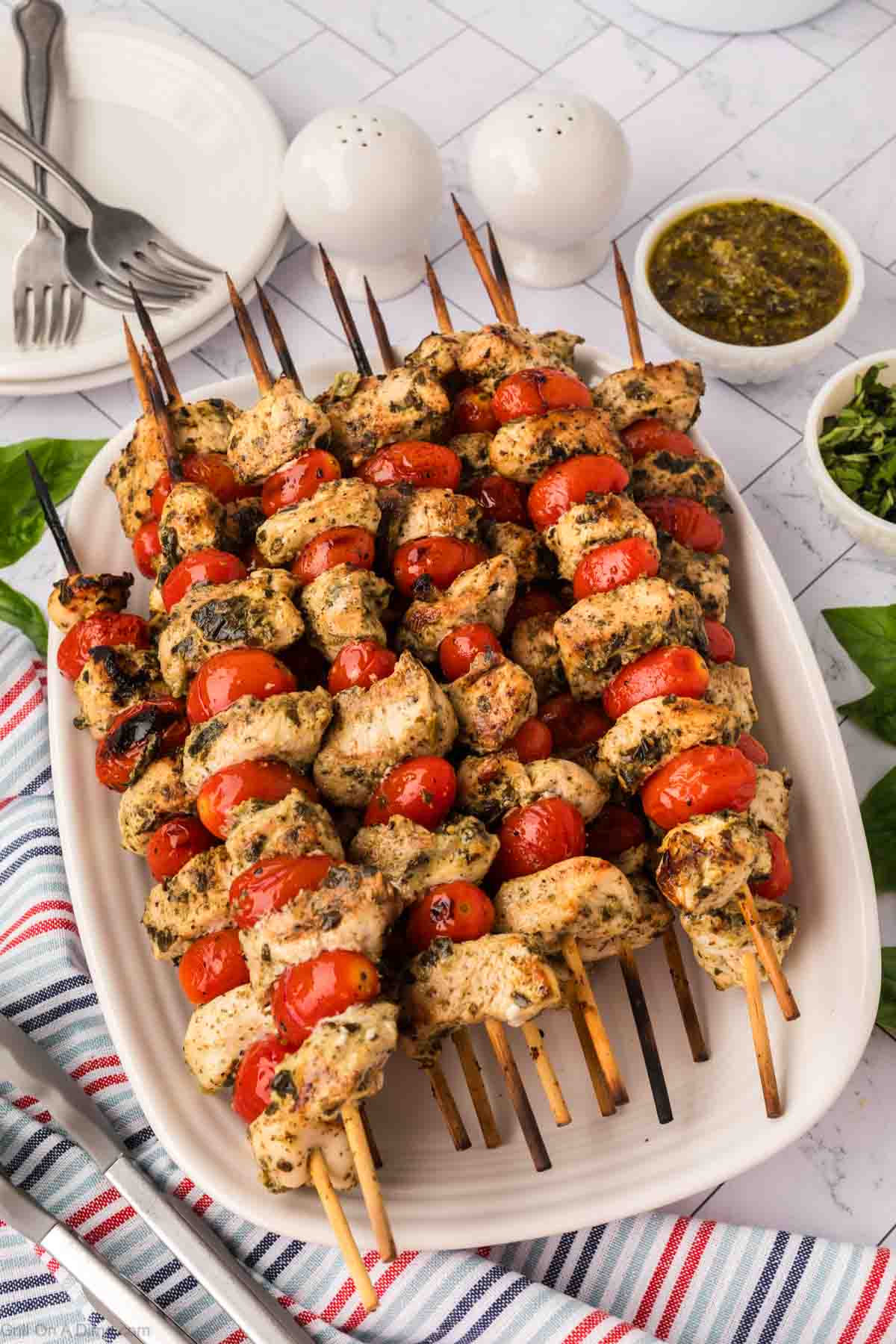 Grilled Chicken and Cherry Tomatoes kabobs stacked on a white platter