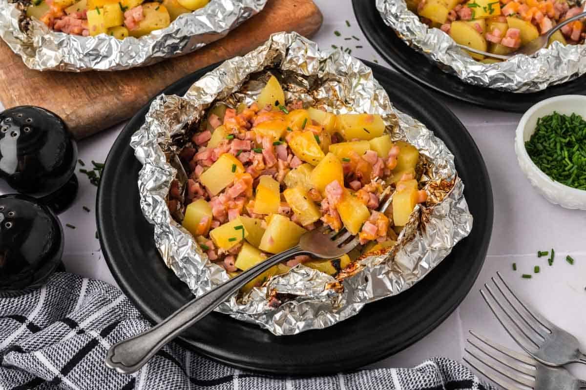 Diced potatoes and ham on a piece of foil on a black plate