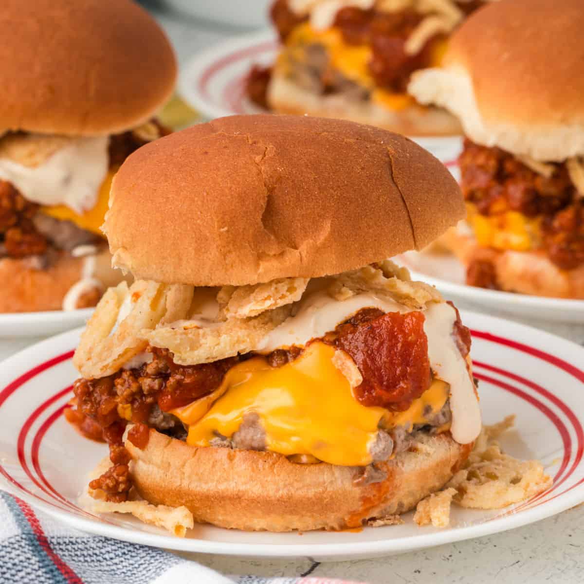 Two hamburgers with cheese and chili on them.
