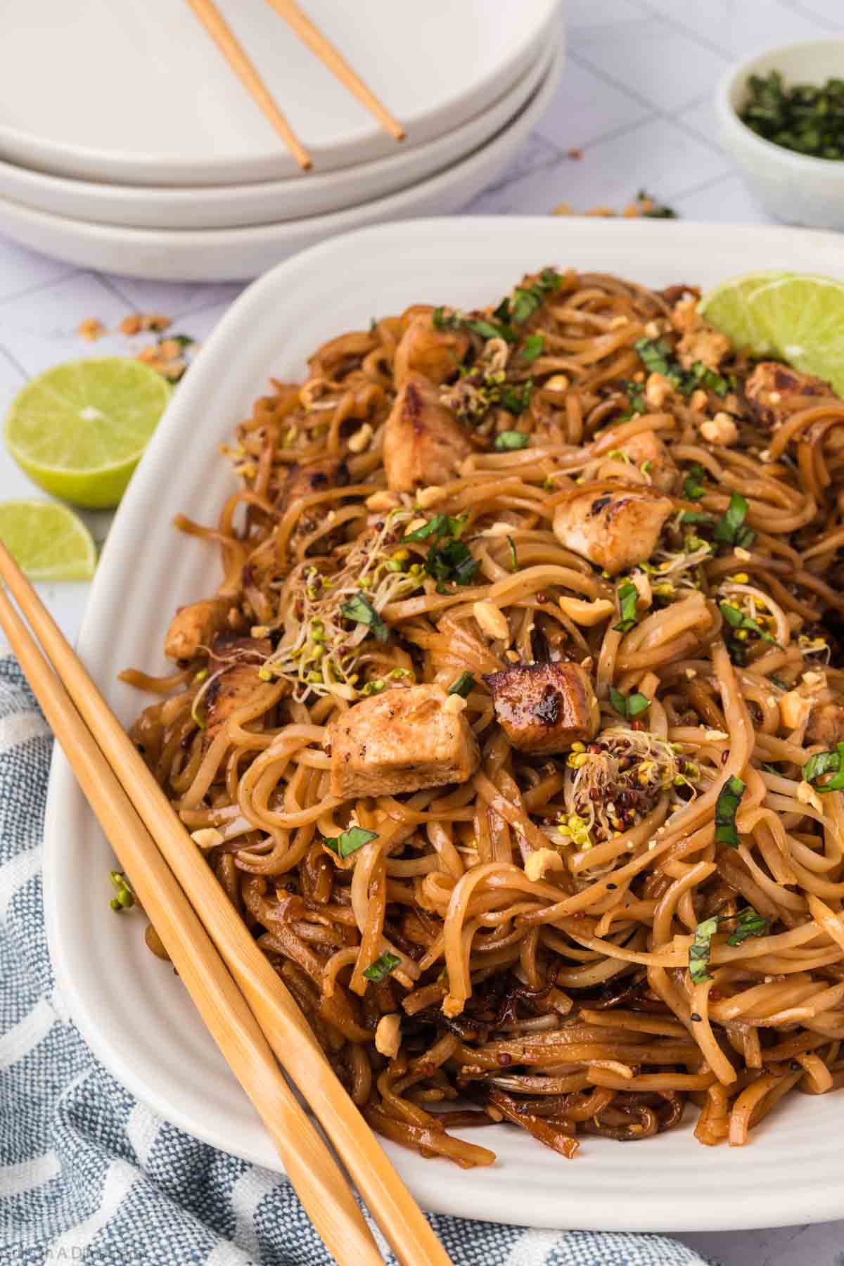 A serving of Pad Thai on the a white platter with chopsticks