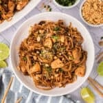 Chicken pad thai in a white bowl with chopsticks.