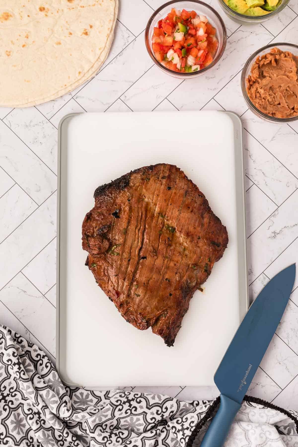 Sliced cooked flank steak on a cutting board