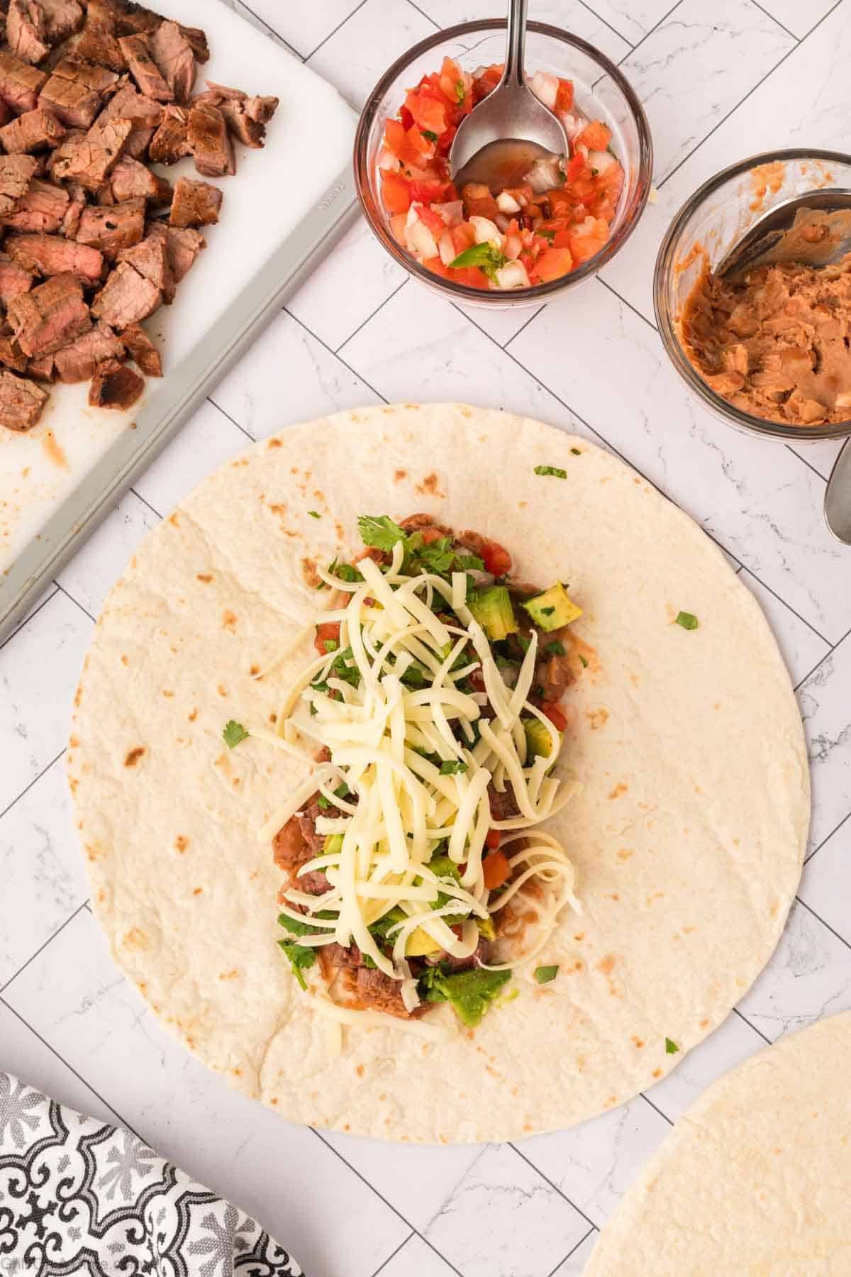 Flour tortilla topped with refried beans, steak, cilantro and shredded cheese