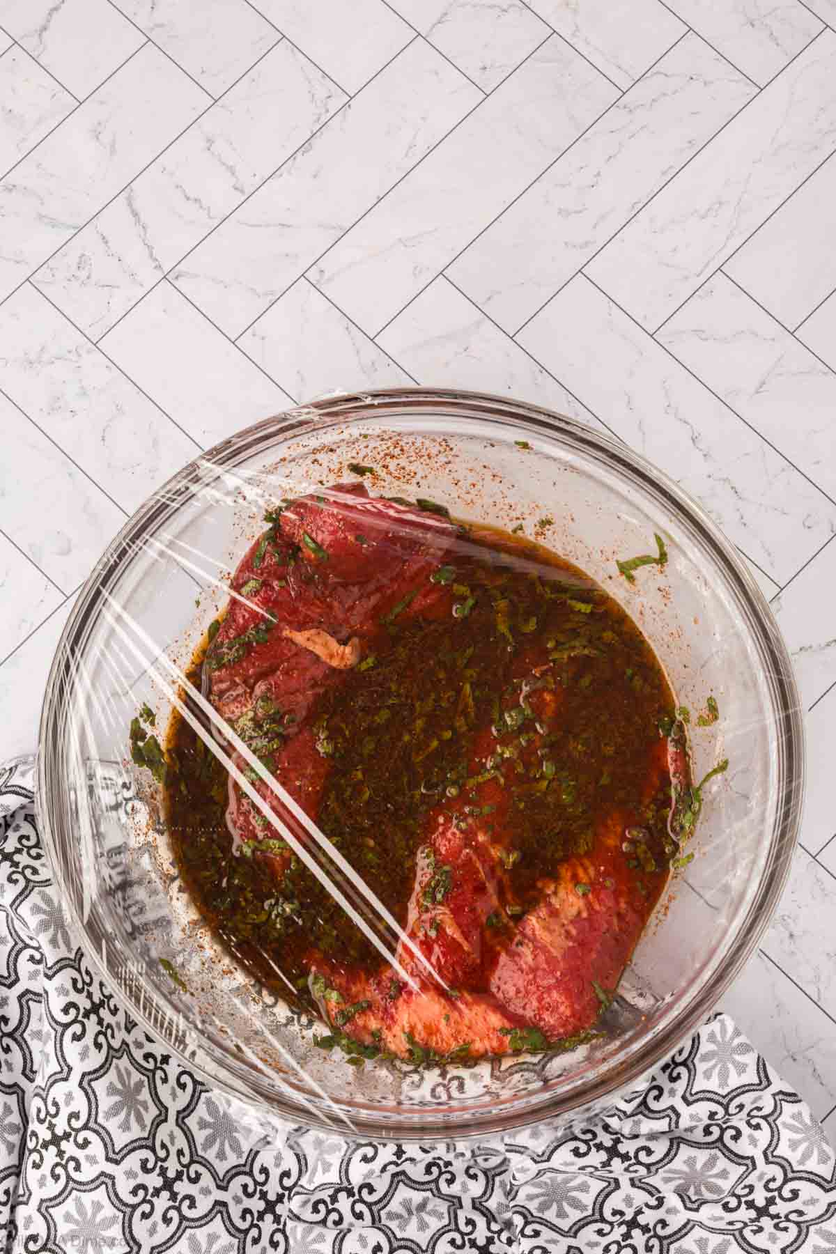 Covering the beef with the marinade in the bowl