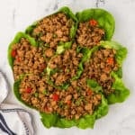 A plate of lettuce wraps with meat and vegetables.
