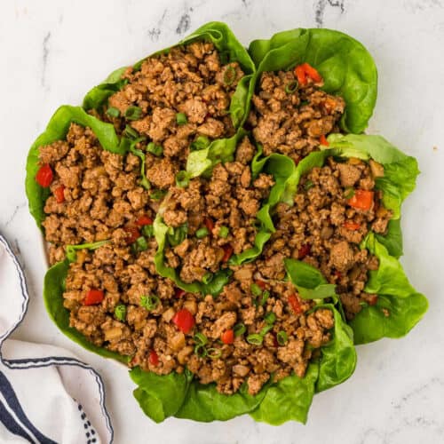 A plate of lettuce wraps with meat and vegetables.
