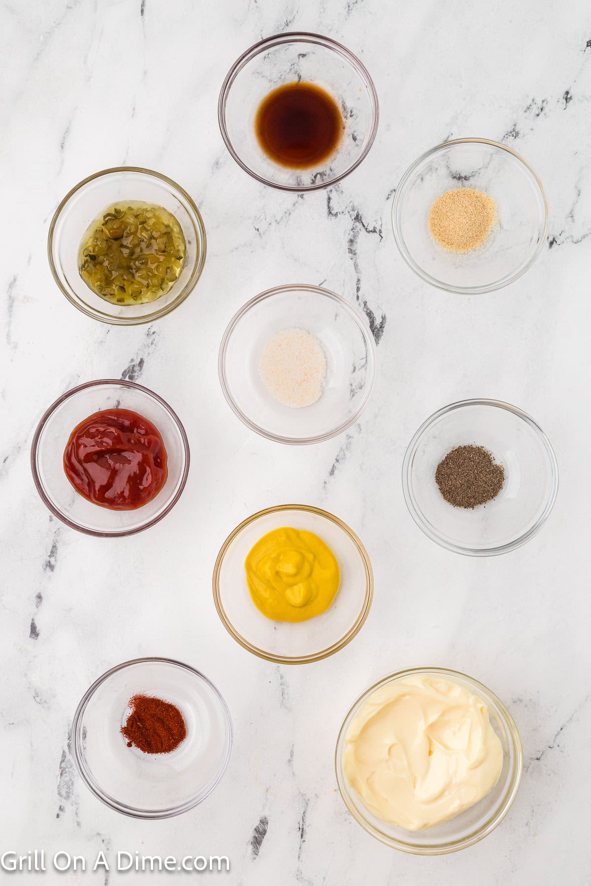 Ingredients in small bowls, mayonnaise, ketchup, mustard, relish, worcestershire sauce, garlic salt, onion powder, pepper, smoked paprika