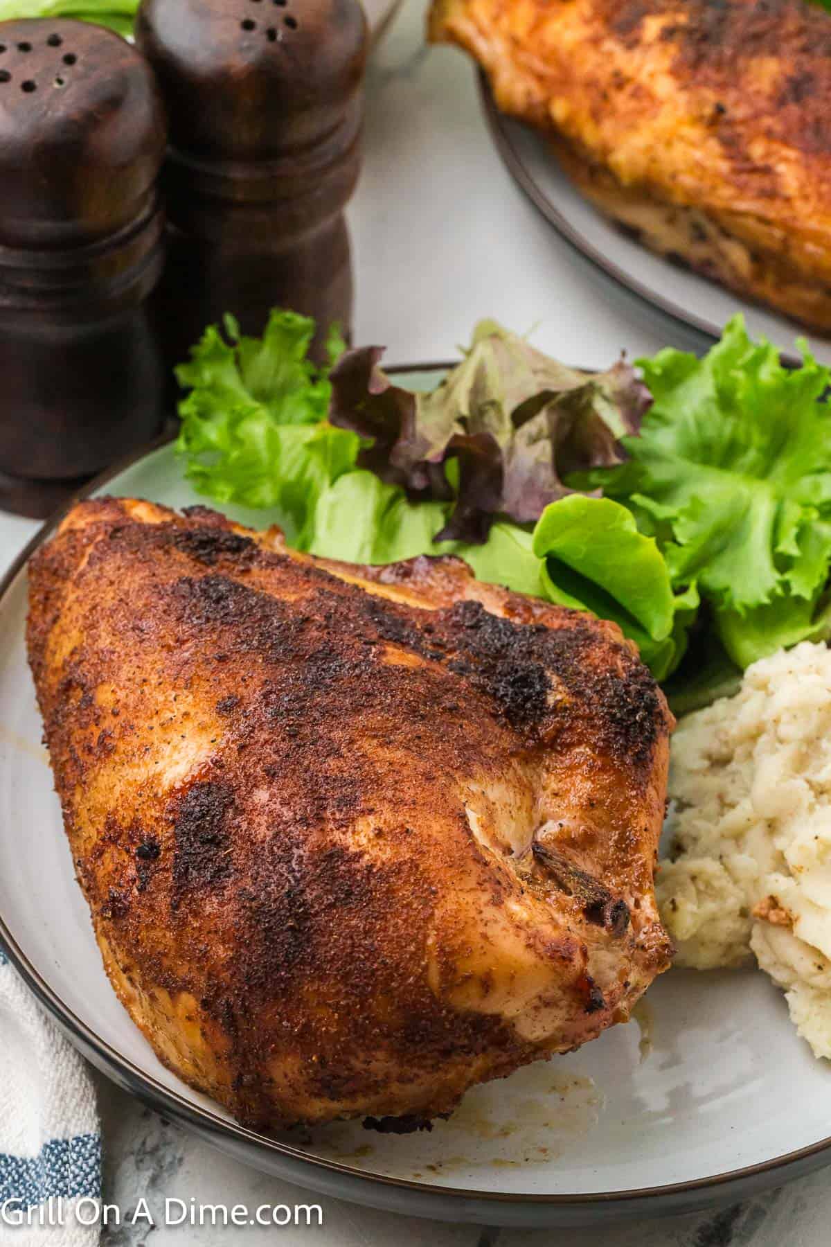 Smoked chicken breast on a plate with a side of green salad and mashed potatoes