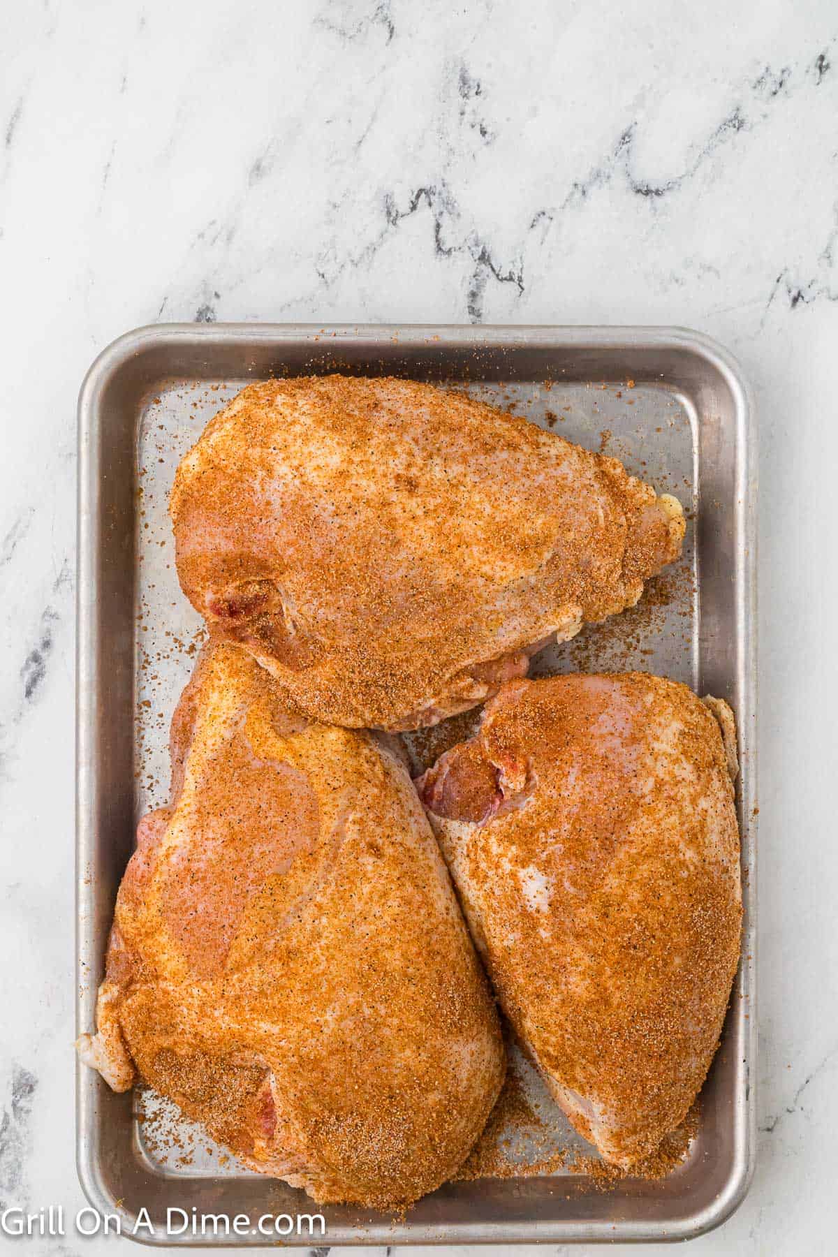 Seasoned chicken breast on a baking sheet