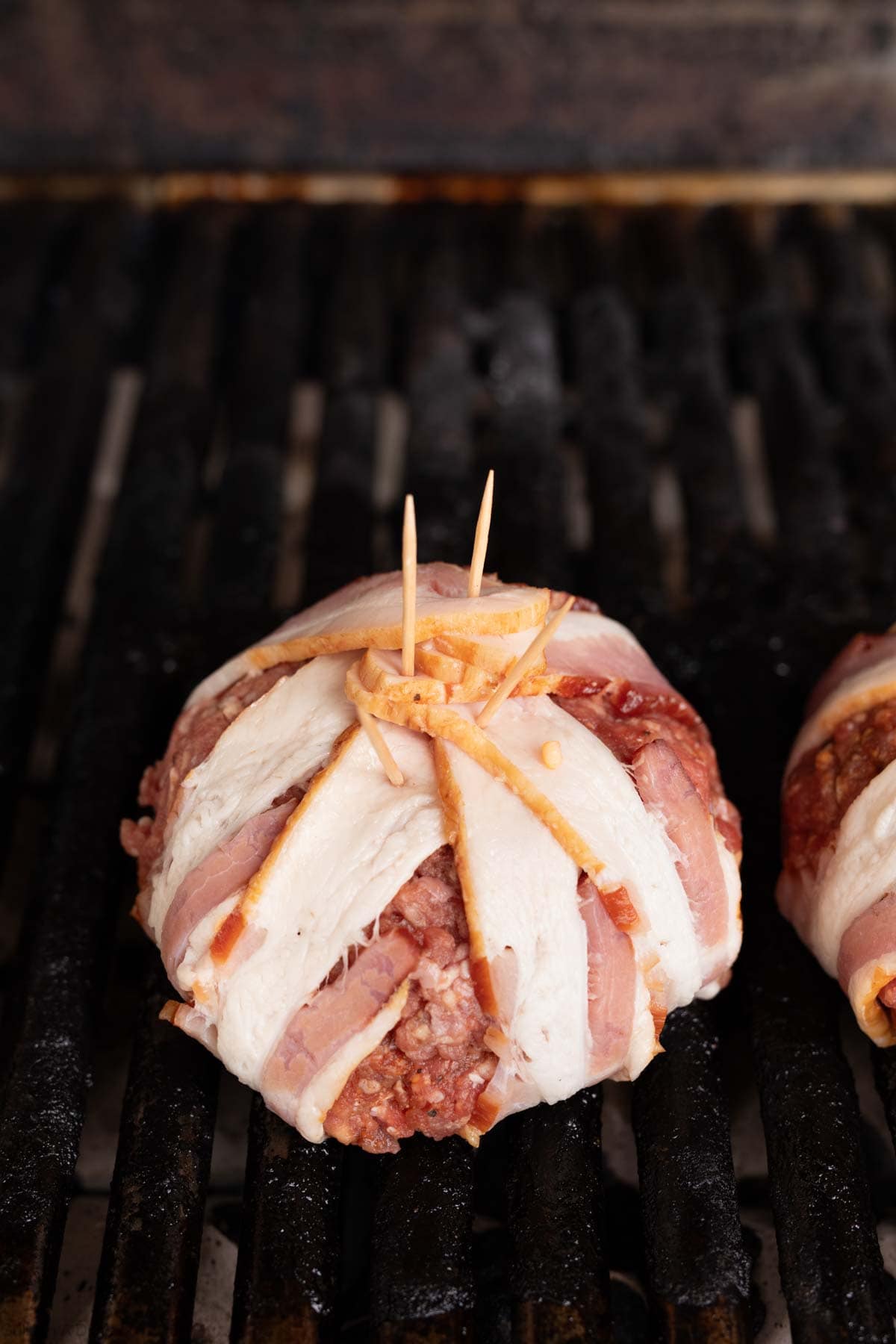 Placing the bacon wrapped ground beef ball on the grill