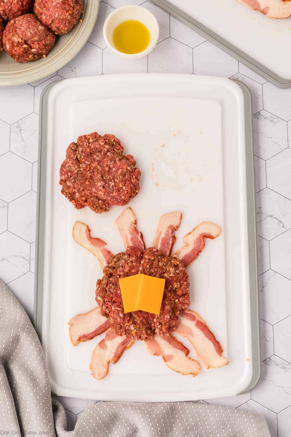 Ground beef pattie on bacon strips topped with cheese slices