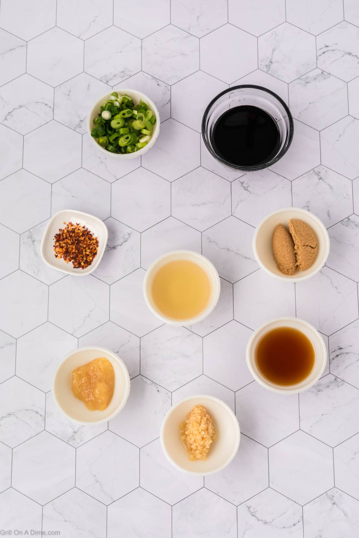 Ingredients - small bowls of soy sauce, brown sugar, sesame oil, rice vinegar, garlic cloves, ginger, red pepper flakes, and green onions