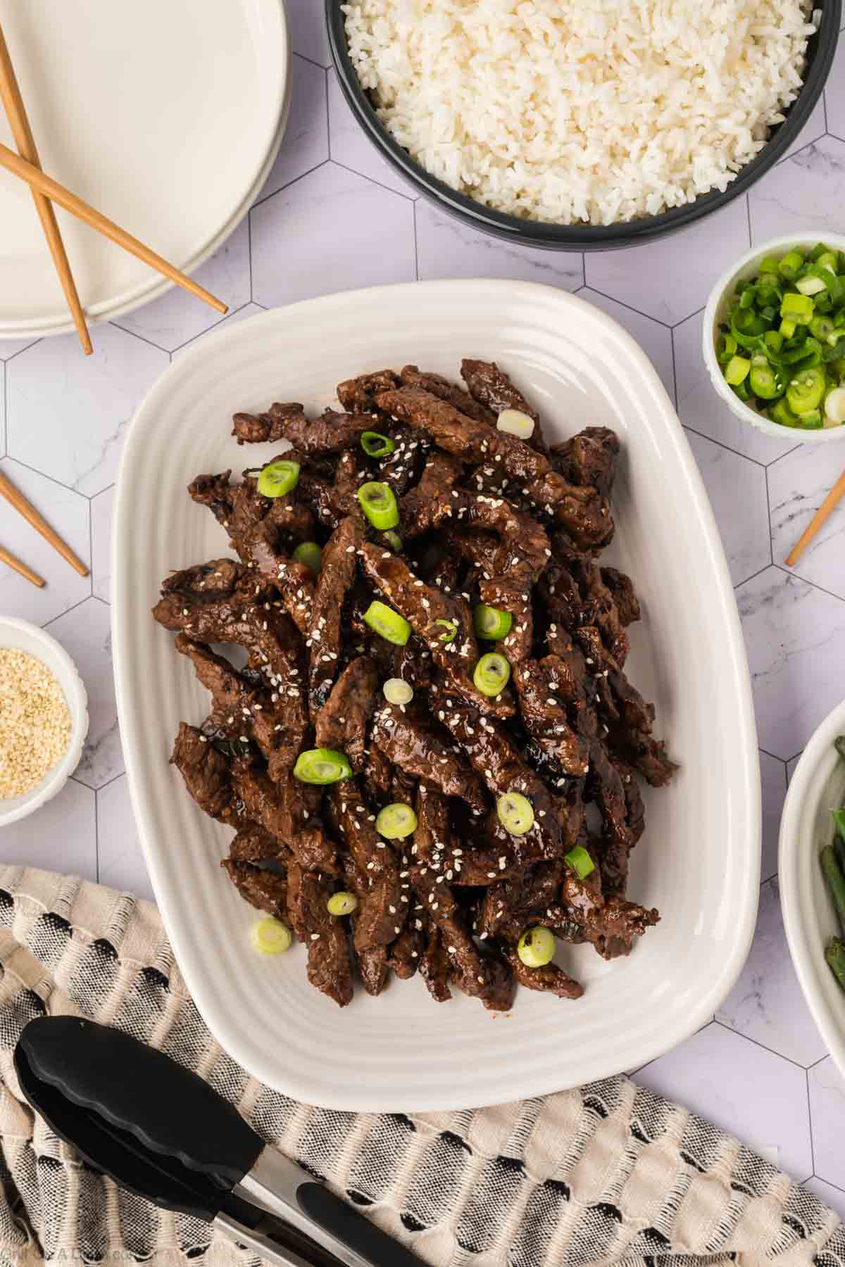 Korean BBQ Beef topped with green onions and sesame seeds on a platter