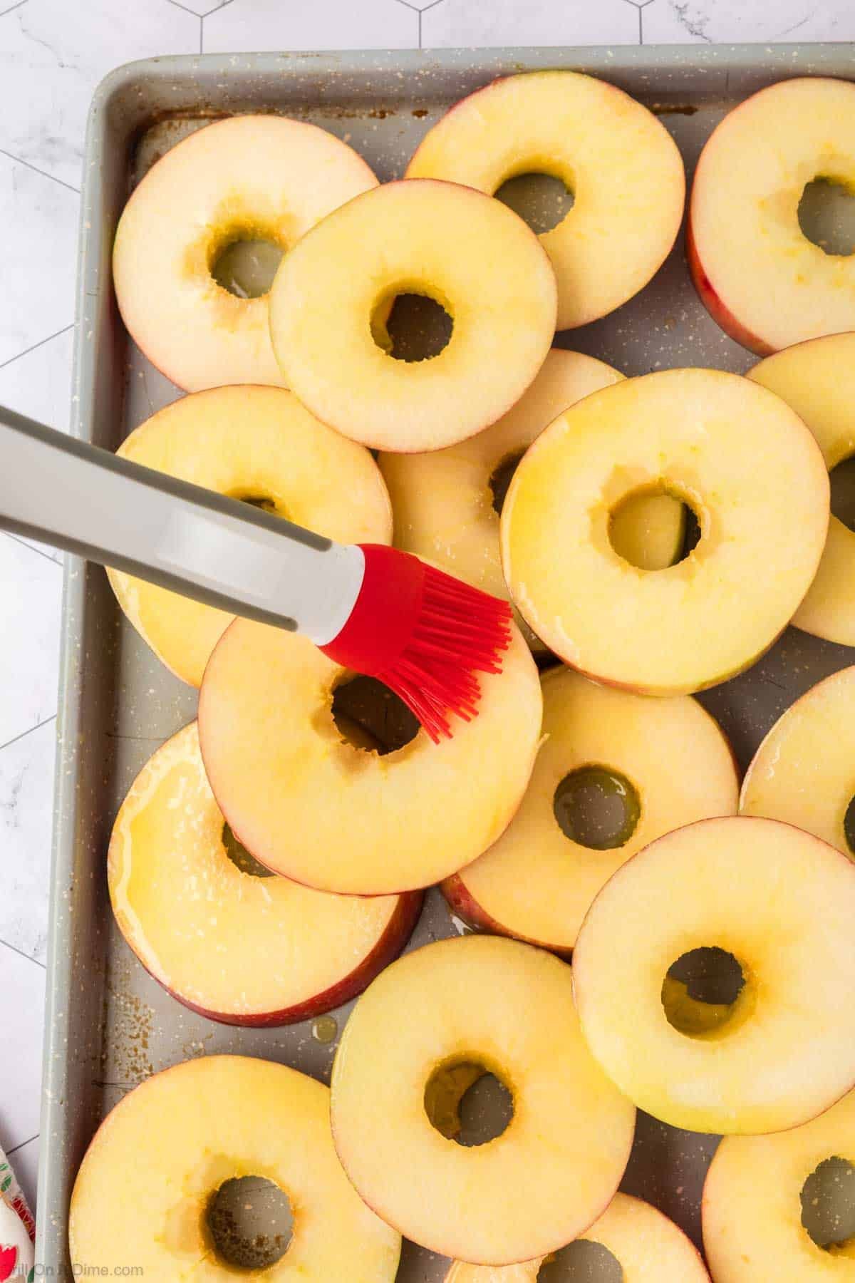Brushing the oil onto the apple slices on the baking sheet