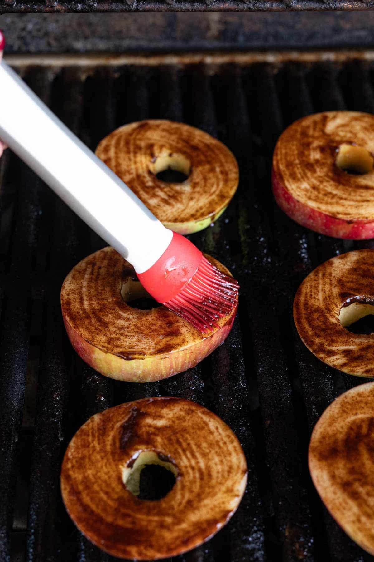Brushing the cinnamon mixture onto the apple slices on the grill grates