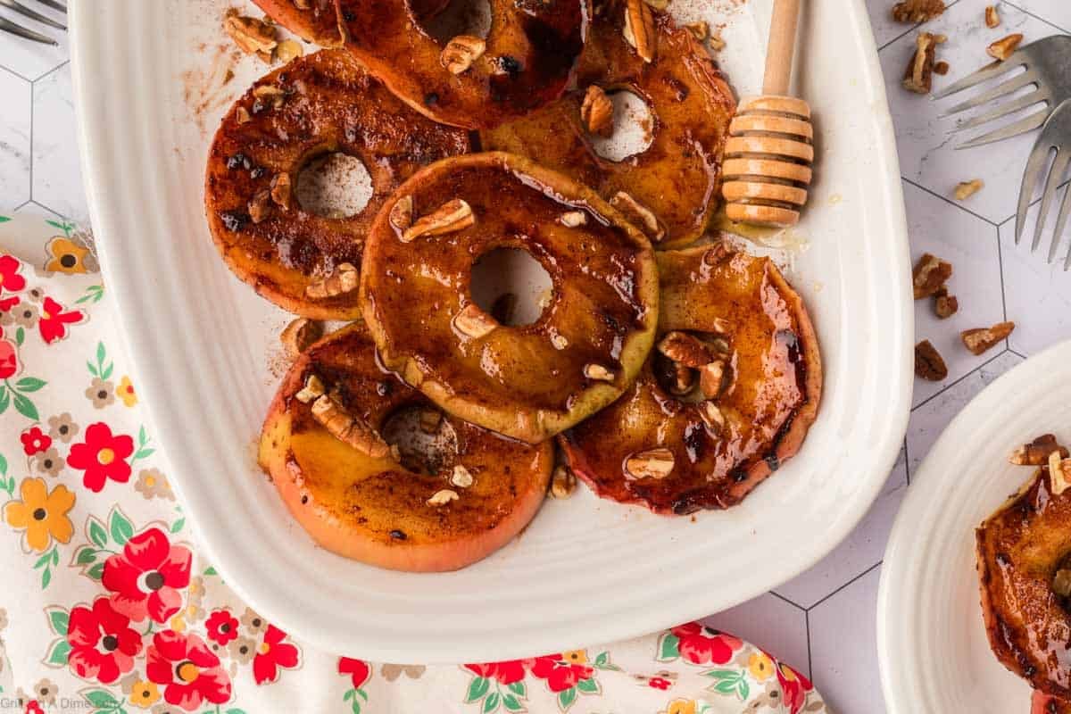 Grilled Slice Apples on a white platter topped with chopped nuts