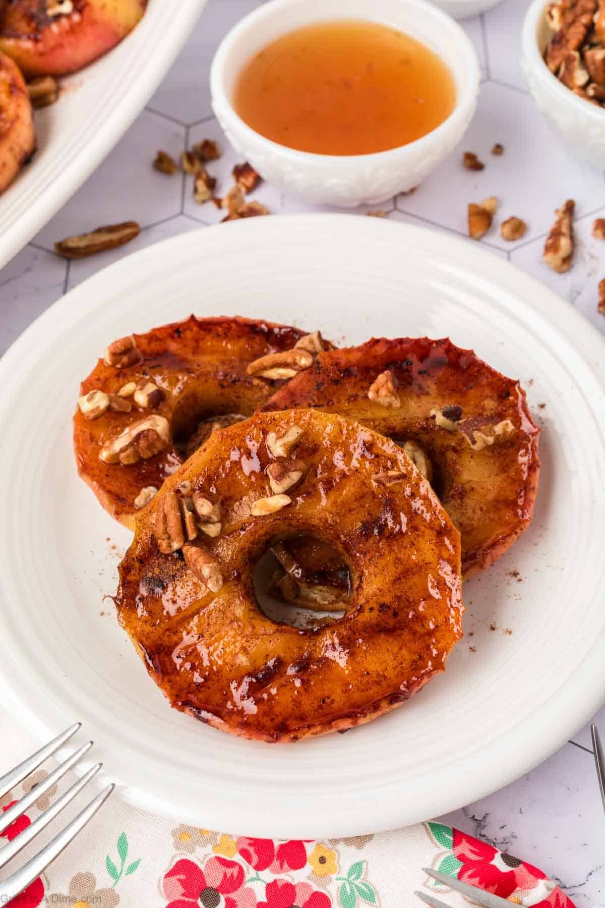 slice caramelized apples topped with chopped pecans on a plate
