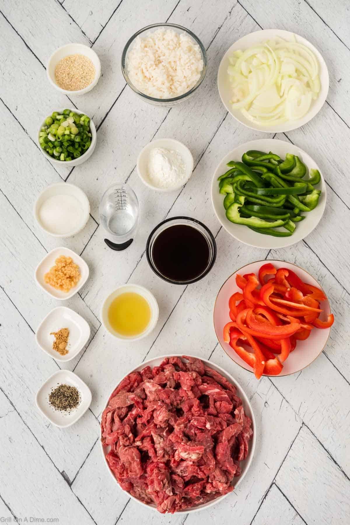 The ingredients required to make the recipe that includes flank steak strips, slice bell peppers, onions, and more. 