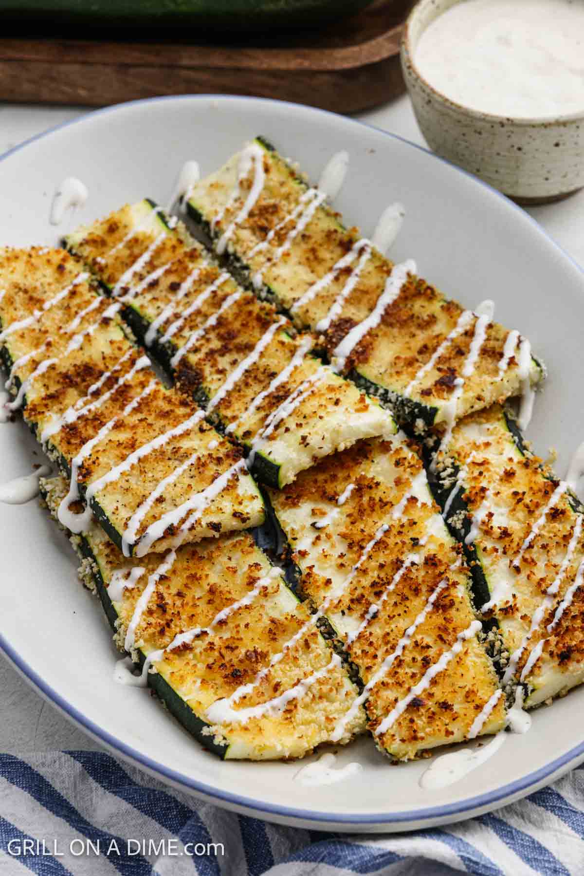 Zucchini with crispy parmesan coating on a platter drizzled with a platter.