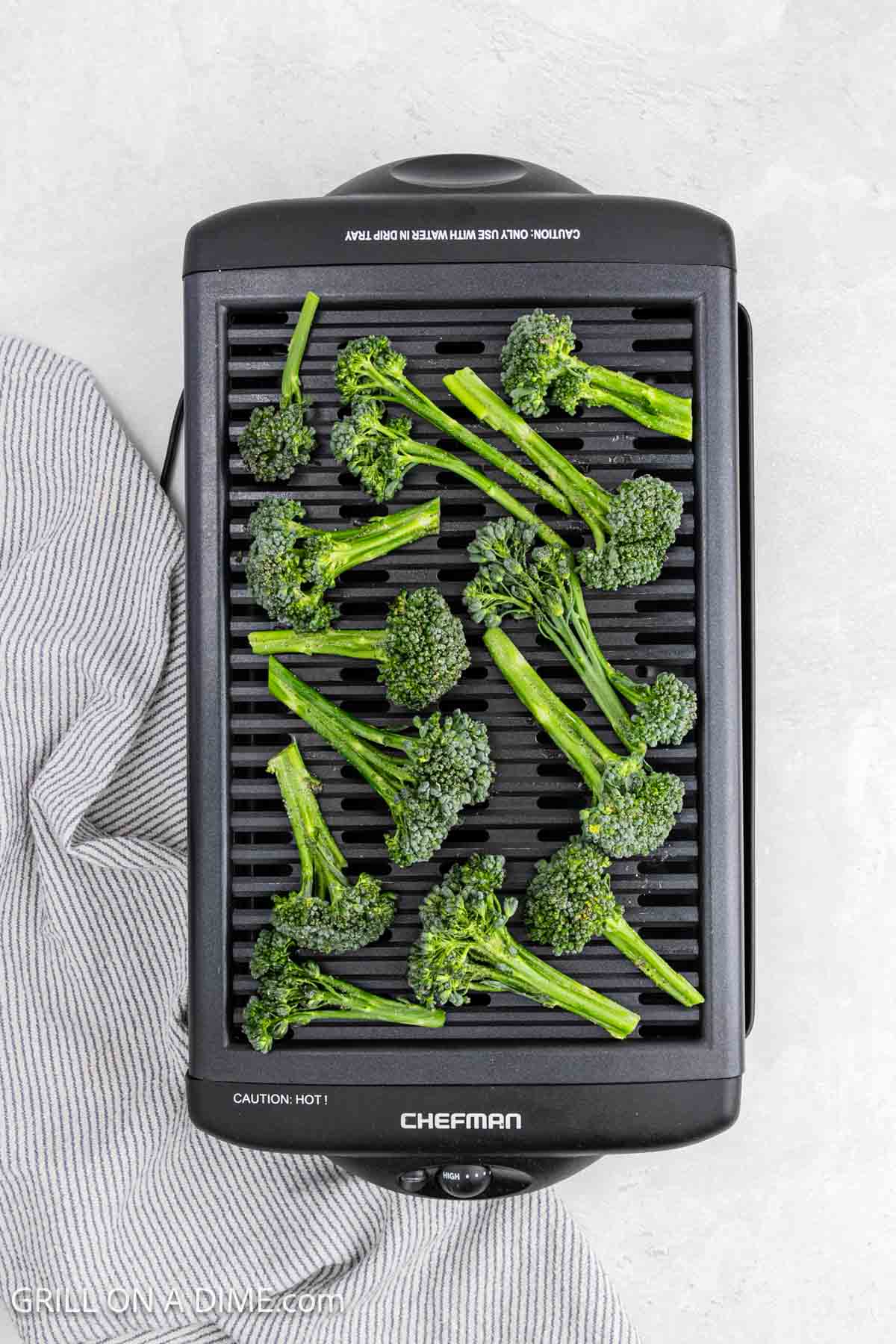 An overhead view of fresh broccoli florets on an indoor electric grill.