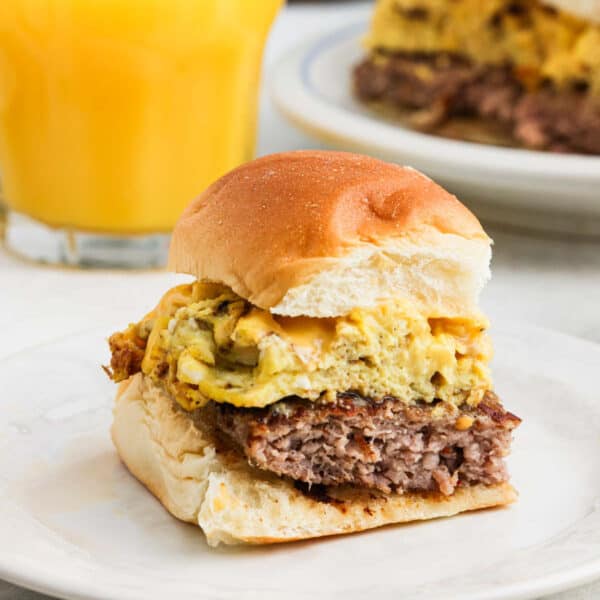 Breakfast sandwich layered with sausage, egg and cheese on a plate.