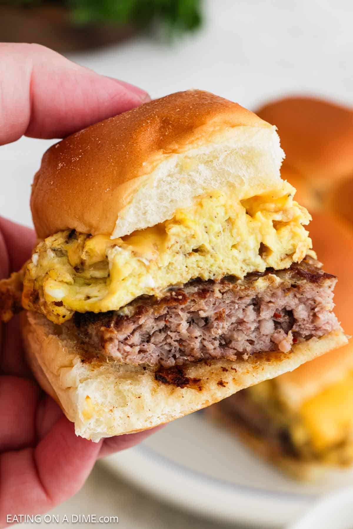 Breakfast sliders being held up close with a hand. 