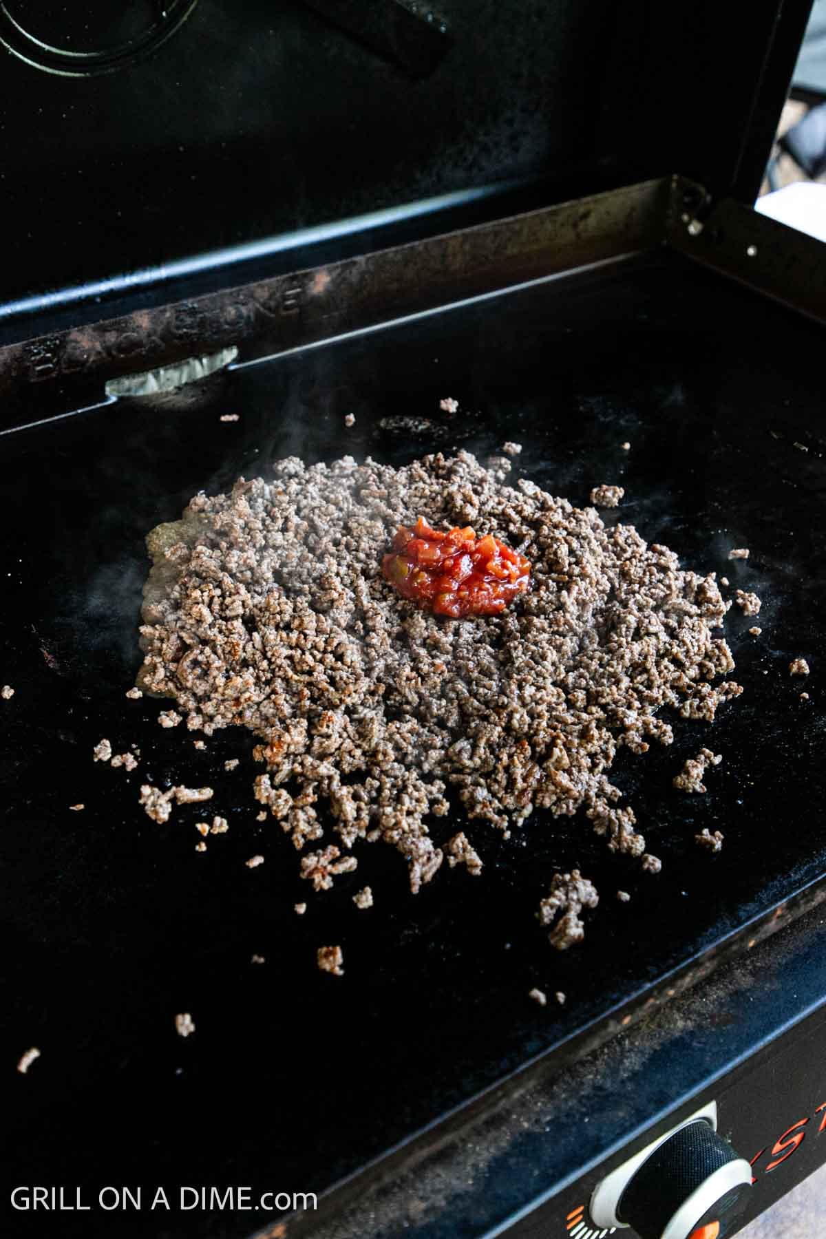 Cooked ground beef on the Blackstone Griddle topped with salsa.