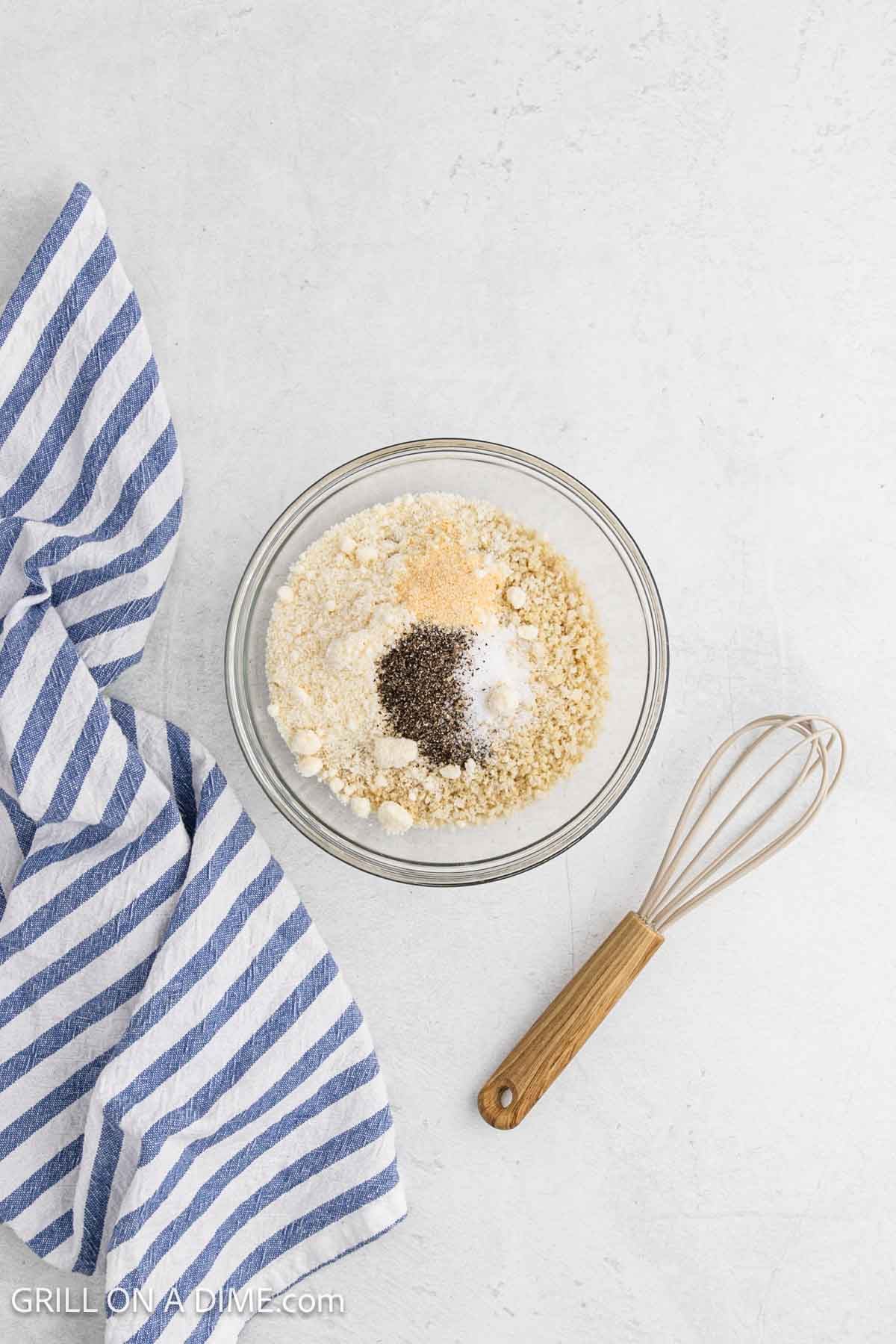 Combining the parmesan, breadcrumbs and spices together in a bowl with a whisk.