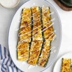 Parmesan crusted zucchini drizzled with ranch on a platter.
