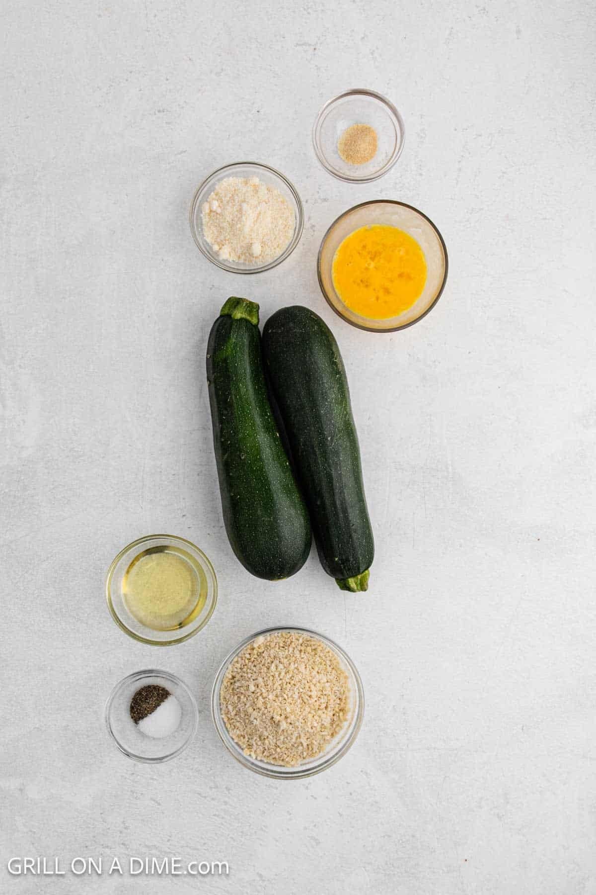 Ingredients needed for this recipe includes zucchini, egg, breadcrumbs, parmesan cheese, salt, pepper, garlic powder, and avocado oil.