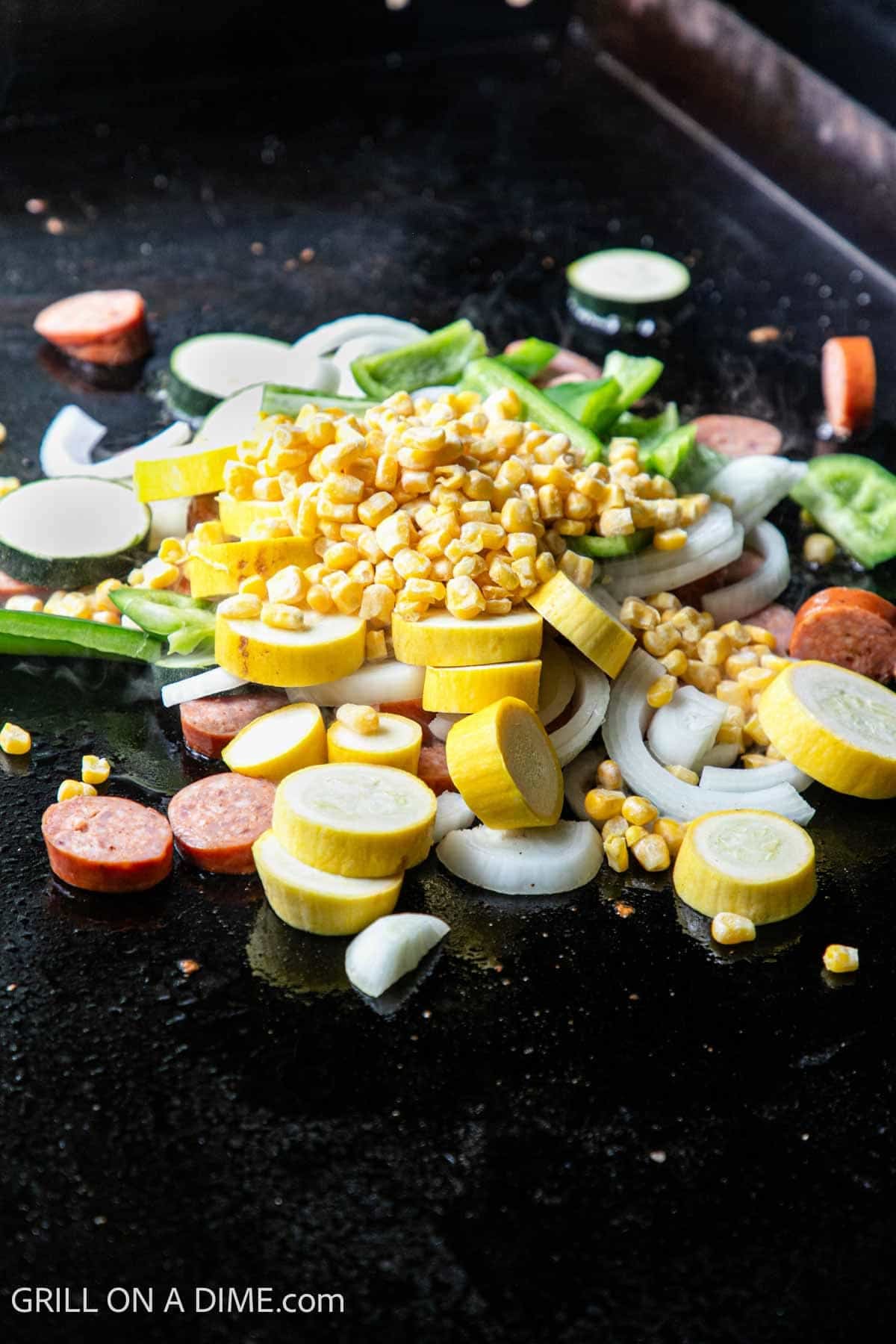 Slice squash, zucchini, corn, onion, and sausage cooking on the Blackstone Griddle. 