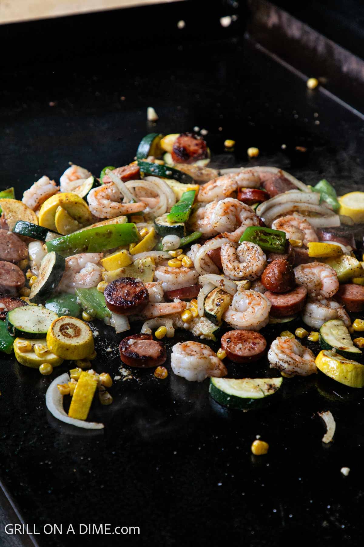 Shrimp added to the cooked vegetable and sausage mixture on the griddle. 