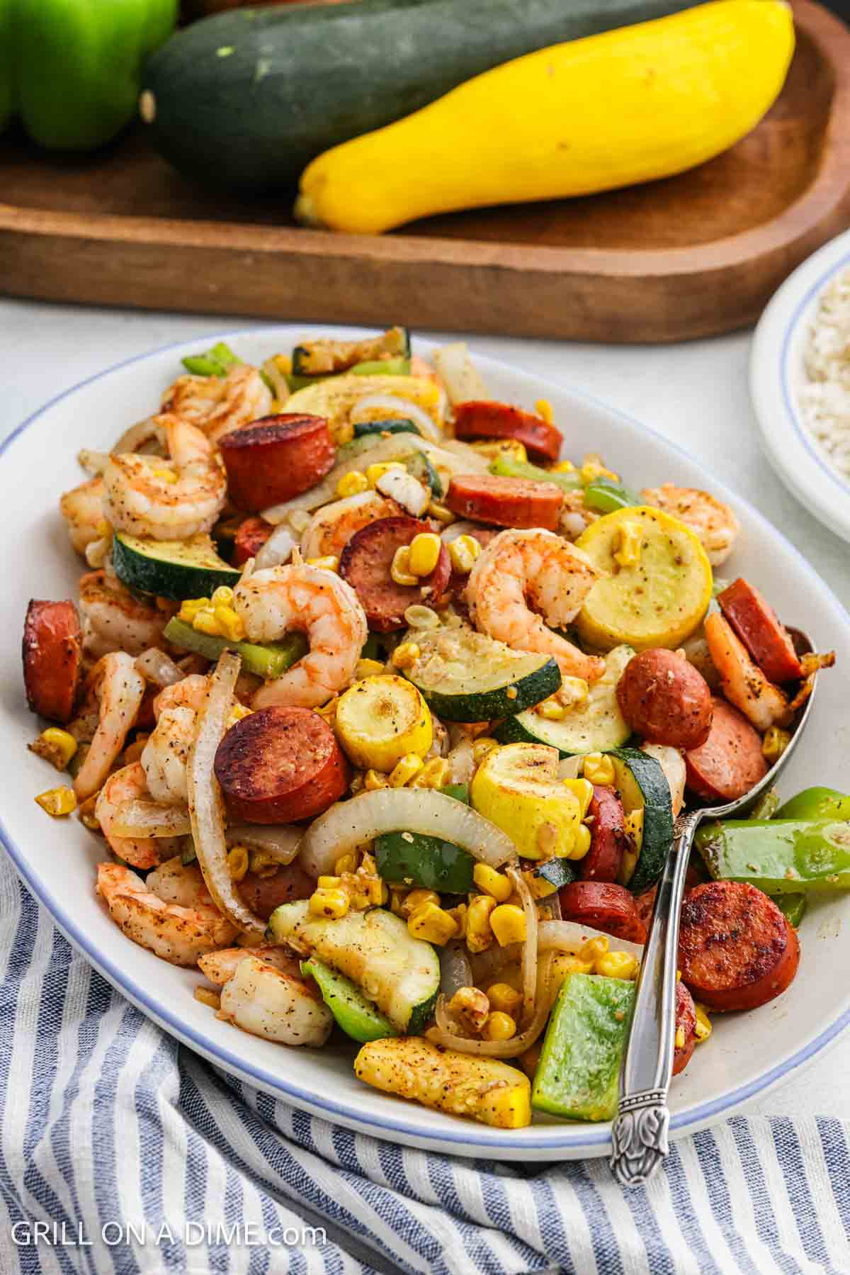 Cooked shrimp, vegetables, and sausage on a platter. 