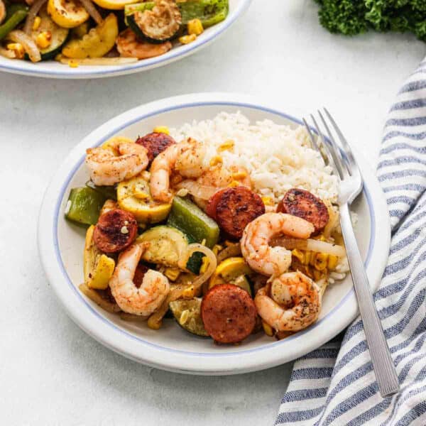 Shrimp, Sausage and Vegetable stir fry on a plate with a side of white rice.