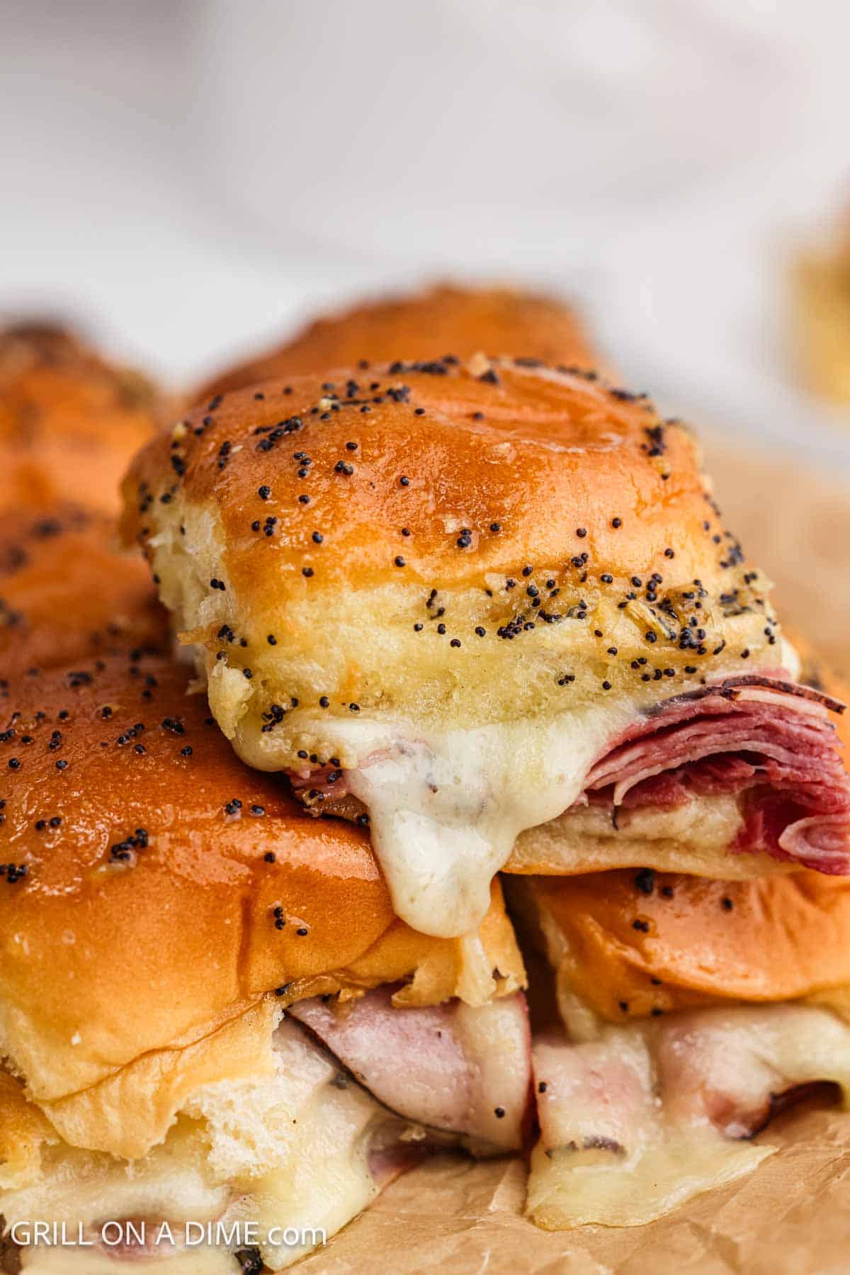 Ham and melted cheese sliders stacked. 