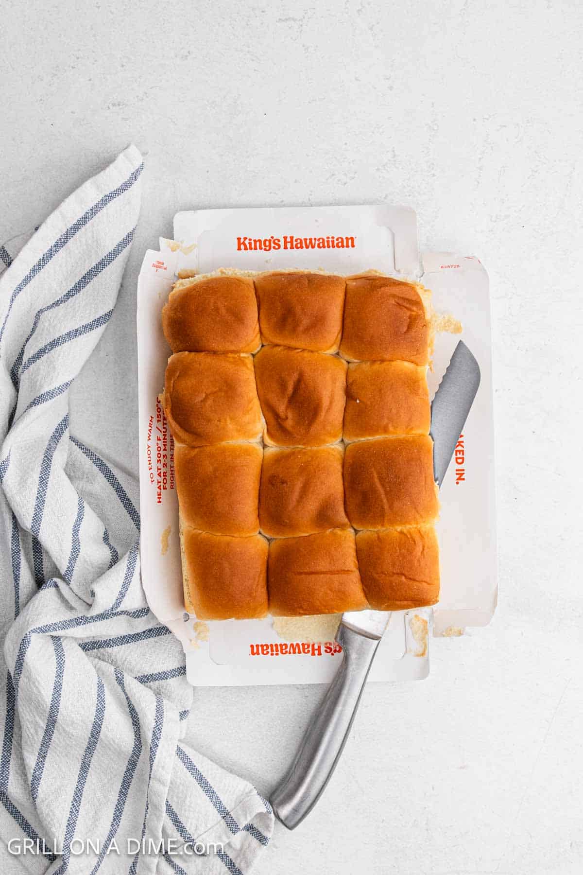 Slicing the Hawaiian Rolls in half with a knife. 