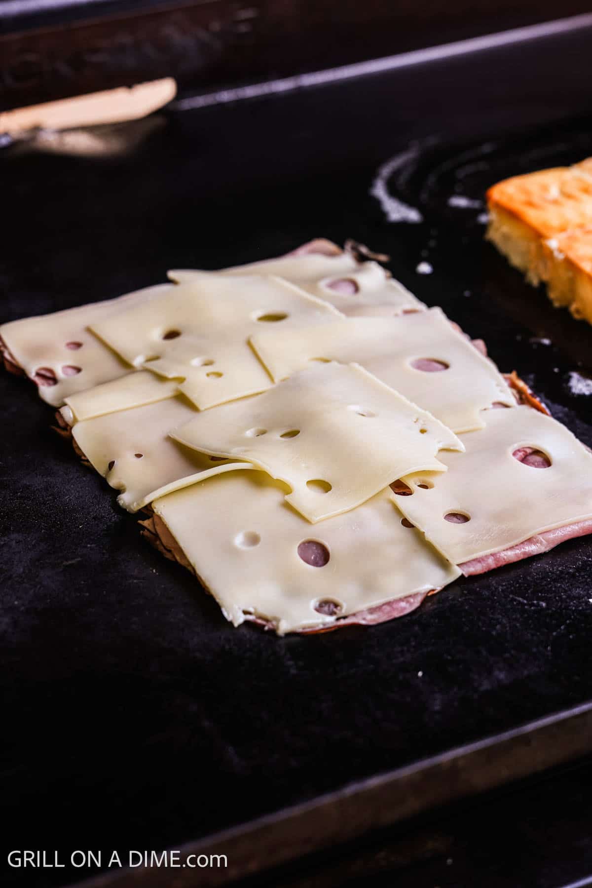 Slice cheese placed on the deli ham on the griddle. 