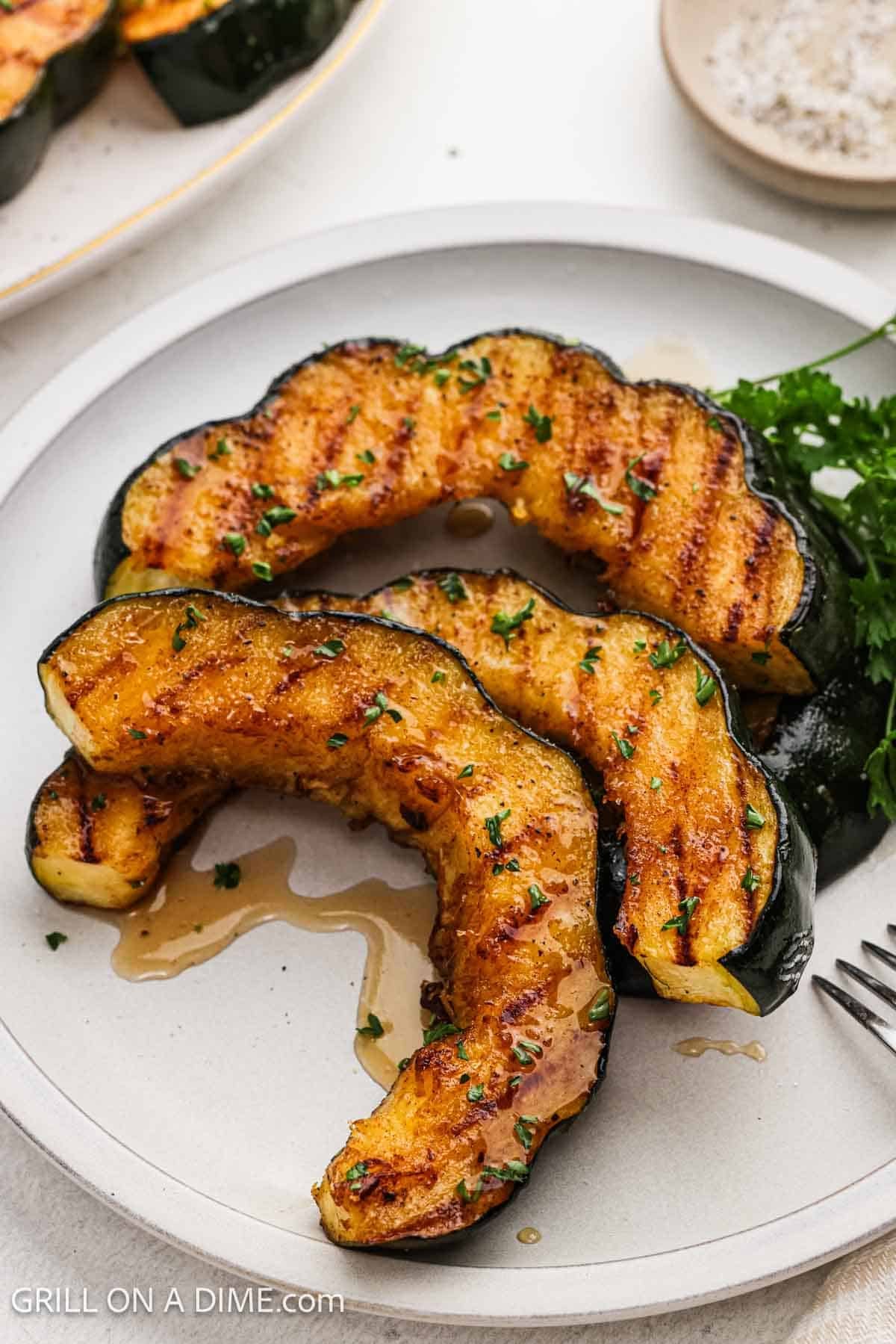 Acorn squash with grill marks stacked on a platter.