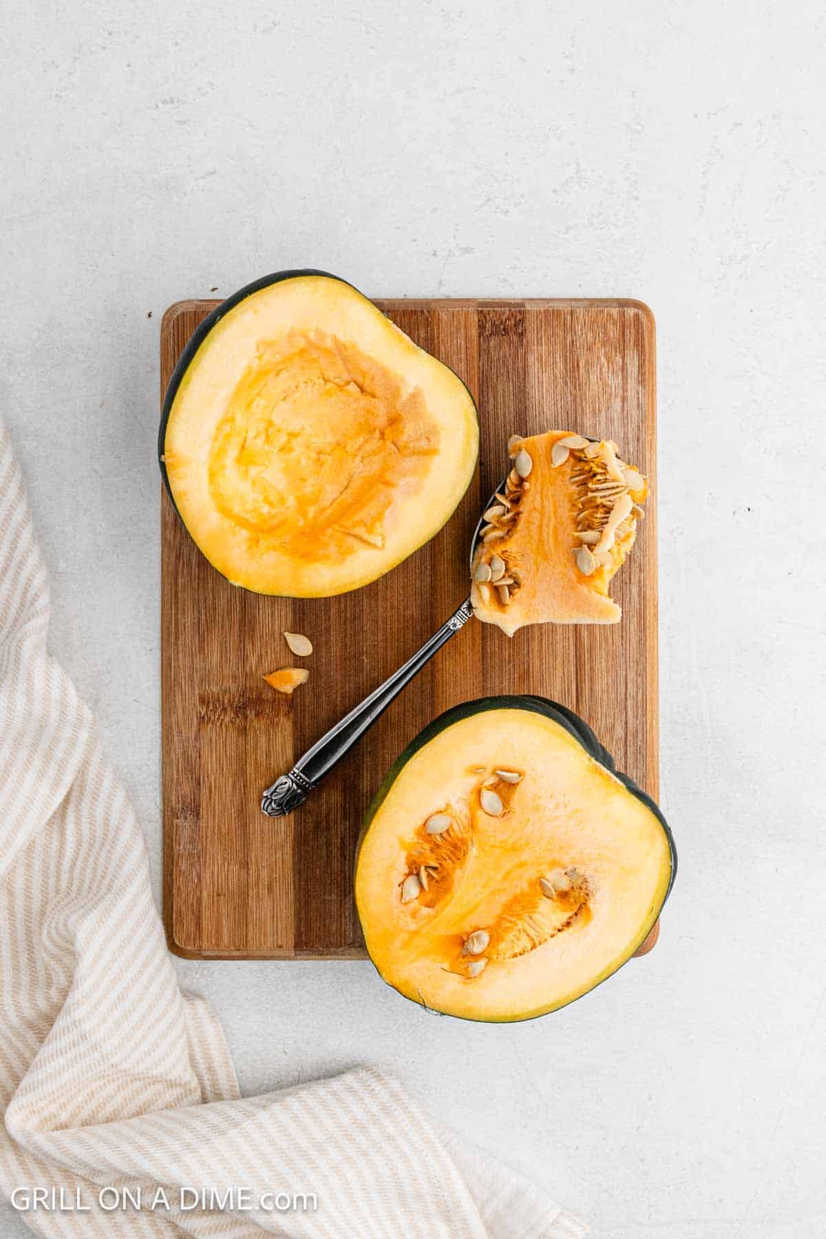 Acorn Squash sliced open on a cutting board to remove the seeds.