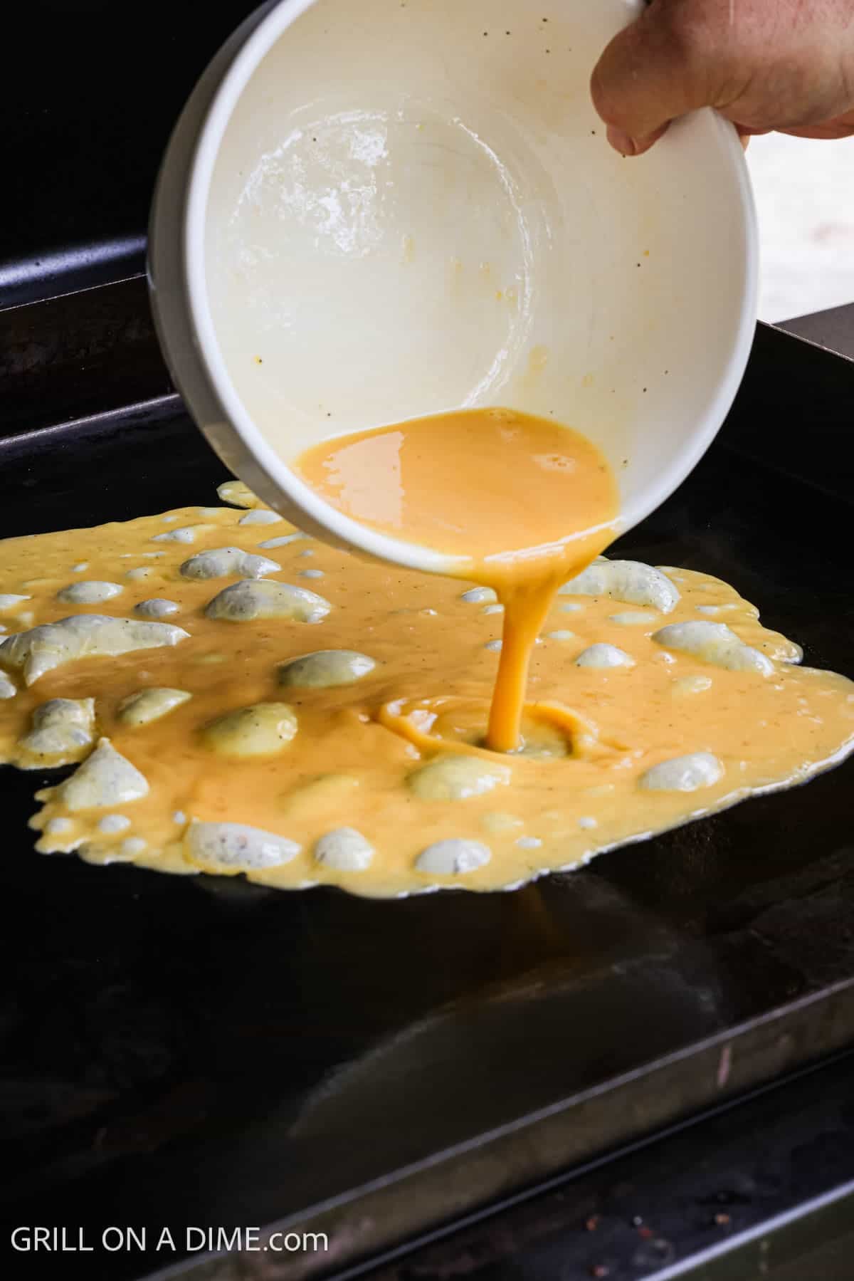 Pouring eggs on the flat top grill. 